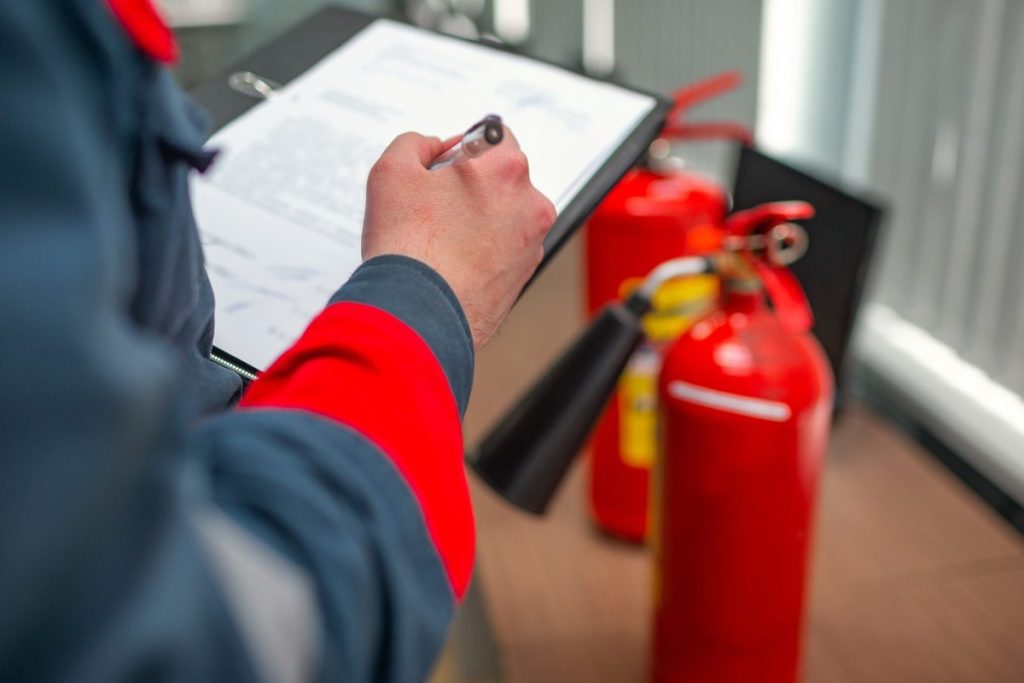 A fire extinguisher with a clipboard in front of it, showcasing a FHDS report.